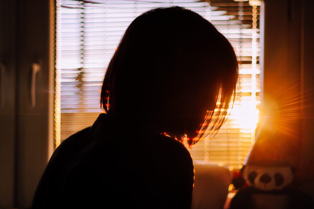 The silhouette of a woman in front of a sunny window